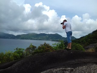 The man on the cliff taking pictures of the seascape