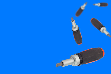 Lot of falling ratchet screwdriver with orange and black plastic with rubber handle and bit on blue background with copy space for your text