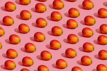 Pattern composition of a sweet tasty mango lying next to a pink background , top view
