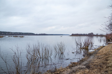 Deep calm river in the spring evening against a cloudy sky