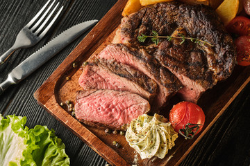 Juicy steak with fragrant butter. Sliced Ribeye Steak with Potatoes, Onions and Baked Cherry Tomatoes