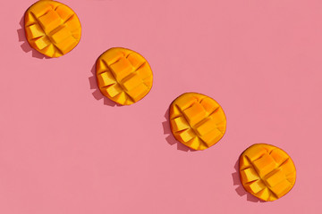 Colorful fruit pattern of fresh juicy cutted mango on coral pink background, top view
