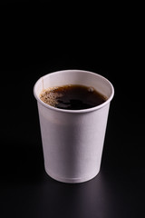 coffee pouring into disposable paper cup on a black background, takeaway coffee cup, moke up