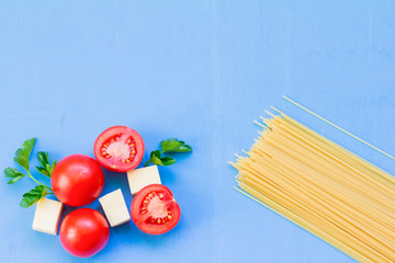 spaghetti and cooking ingredients on blue wooden background