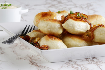 closeup crispy pierogies with spring onions on a plate 
