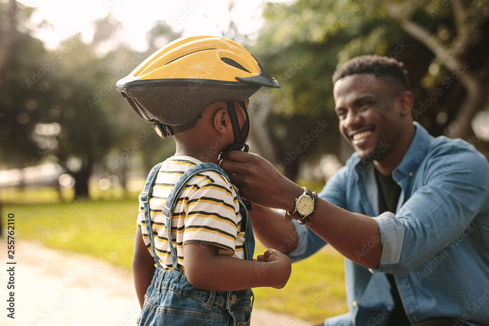 Sticker father helping his son to wear a cycling helmet