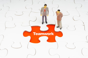 TEAMWORK inscription written on jigsaw puzzle and businessman miniature. Business and motivation concept
