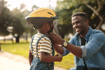 Father helping his son to wear a cycling helmet