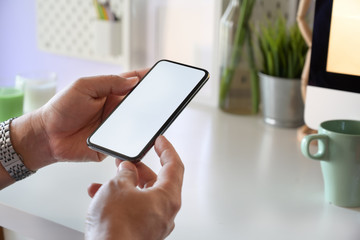 Man holding mockup mobile smart phone device on office workplace
