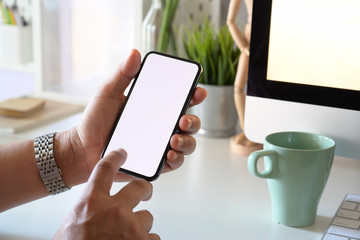 Man holding mockup mobile smart phone device on office workplace