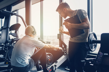 Senior man exercising in gym with his personal trainer.