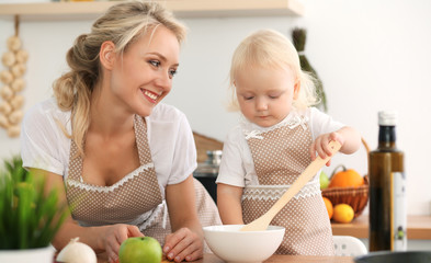 Obraz na płótnie Canvas Happy mother and little daughter cooking in kitchen. Spending time all together, family fun concept