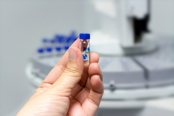 Scientist holds a chemical sample vial. People hand holding a test tube vial sets for analysis.laboratory assistant inserting laboratory glass bottle in a chromatography