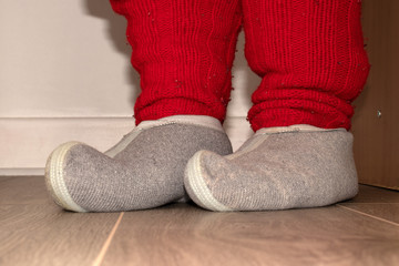 Red knitted socks and woolen slippers on the feet