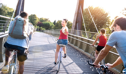 Happy friends millennial having fun riding bike at city park - Friendship concept with young...