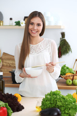 Young happy woman cooking in the kitchen. Healthy meal, lifestyle and culinary concepts. Good morning begins with fresh salad