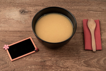 a bowl of soup and empty chalkboard on wooden table