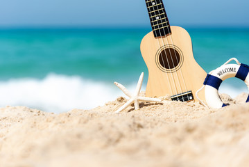 The Summer day with Guitar ukulele for relax on the beautiful beach and blue sky background, copy space. Travel and Summer Concept