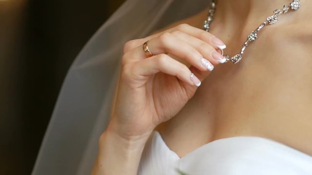 Bride with delicate hands held choker, necklace on the neck. Wedding morning of the bride. Advertising jewelry.