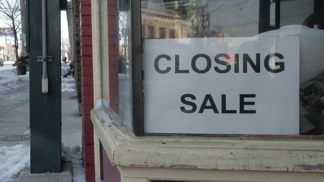 Close up of a closing sale sign in the window of an old store which is going out of business.