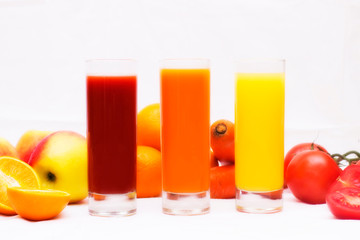 Various vegetable and fruit juices in glass with tomato, carrot, orange and apple an background