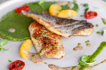 Closeup fried sea bass fillet with green pea puree, tomatoes, sauce, orange slices. Concept professional photography, photosession new menu, profession food stylist, flat-lay, freelancer