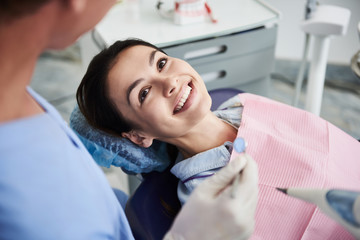 Attractive young lady looking at dentist and smiling