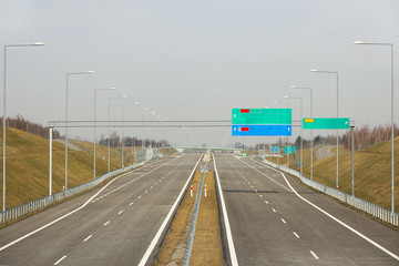 Two-lane motorway with empty road signs. New road without cars. The development of transport infrastructure. Landscape design of the ring road of the metropolis