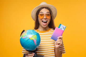 Excited female touristl holding globe in one hand and passport with tickets in other, ready to...