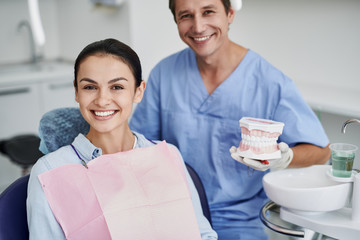Charming young lady and dentist posing at dental office