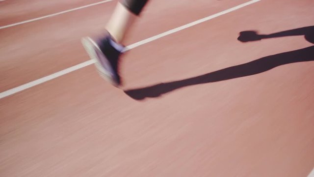 Tracking shot of unrecognizable woman sprinting on running track