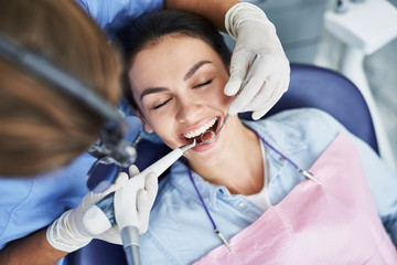 Charming young woman receiving professional teeth cleaning at clinic