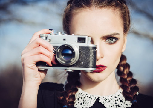 Close-up portrait of beautiful young girl with old film camera in hand