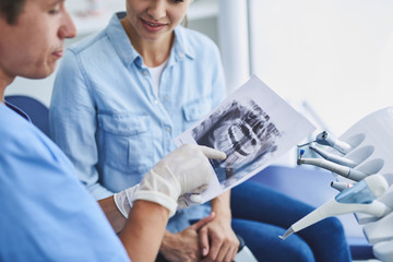 Obraz premium Dentist showing results of orthopantomogram to young lady