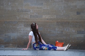Fashionable lady with flower crown sitting on wall