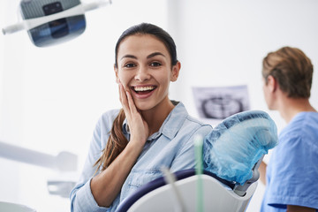 Happy young lady sitting in dental chair
