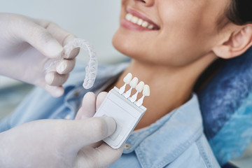 Dentist choosing color of teeth and invisalign braces for lady