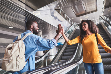 Man and woman giving five standing on escalator