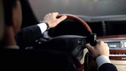 Back view of businessman drinking alcohol in car before driving home, problems