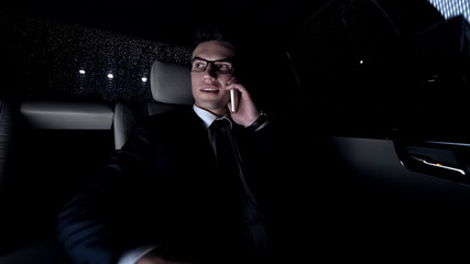 Smiling business person talking on telephone with wife, riding in car, way home