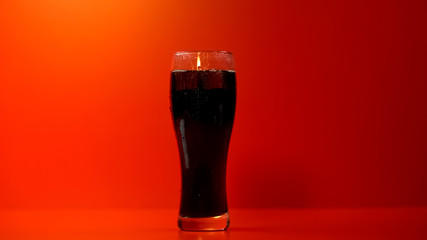 Glass of soda isolated on red background, refreshing but unhealthy beverage