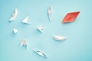 Unsuccessful leadership concept. Red paper boat and a lot of sinking ships