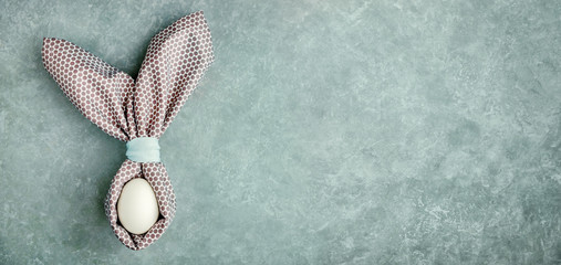 Easter egg decorated with napkin in shape of rabbit ears. Festive easter background