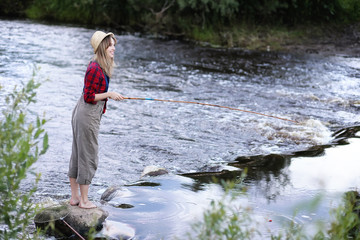 Girl by the river with a fishing rod