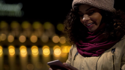 Happy biracial girl in good mood chatting in messenger with boyfriend, laughing