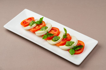 salad with fresh tomatoes, cheese and greens on a white plate