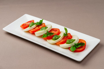 salad with fresh tomatoes, cheese and greens on a white plate