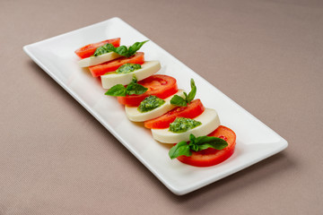 salad with fresh tomatoes, cheese and greens on a white plate