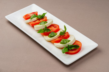 salad with fresh tomatoes, cheese and greens on a white plate