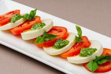 salad with fresh tomatoes, cheese and greens on a white plate